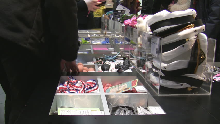 In the souvenir shop shoppers are picking various souvenirs from the stall, you can see sailor hats, Easter eggs and red white and blue colored ribbons