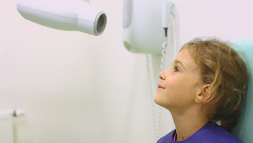 Nurse puts special plate at mouth of girl in lead apron and sets apparatus for x-ray photography