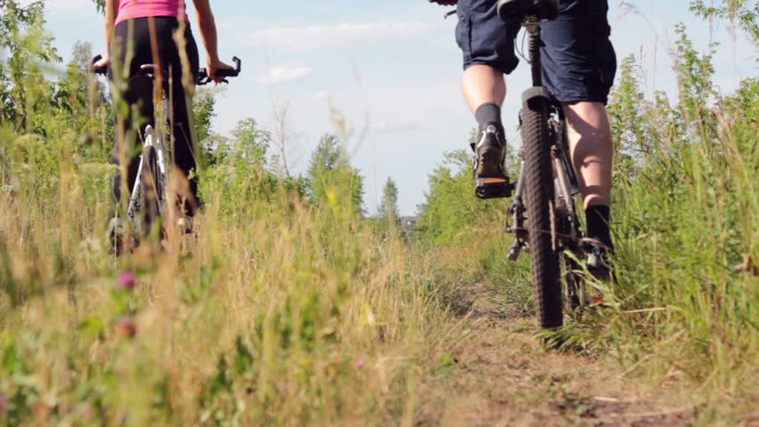 Attractive couple walking with bicycles and drinking water in the forest 