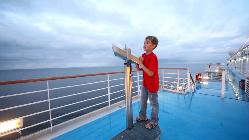 boy in red tee-shirt looks in field-glass on ship deck