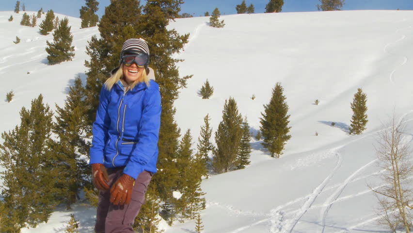 Female snowboarder smiling and throwing hands in the air