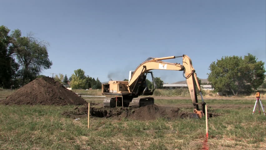 SANPETE COUNTY, UT - SEPT 16: backhoe excavator machine digging a basement for a new house or home. Located in the middle of a farm field. Construction slowdown but not stop.