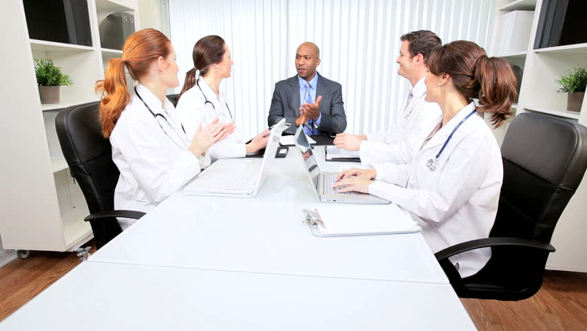 Young multi ethnic medical executives meeting in the boardroom of a modern hospital building