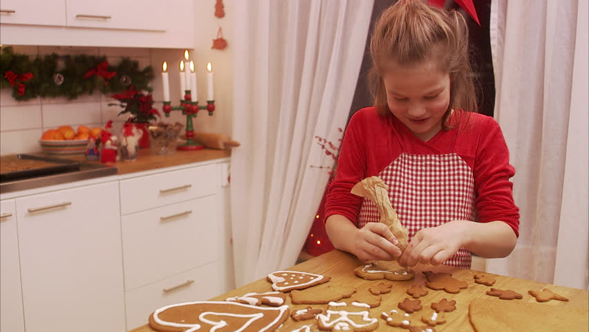 a young girl decorating gingerbread biscuits