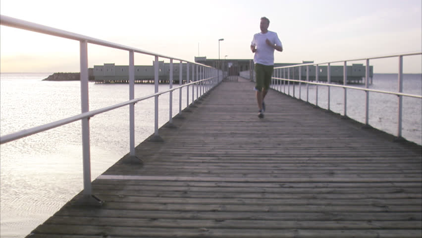 A man jogging on a boardwalk