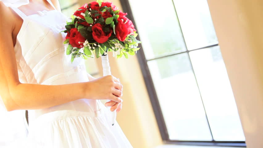 Portrait Caucasian bride with red rose posy home posing photographs
