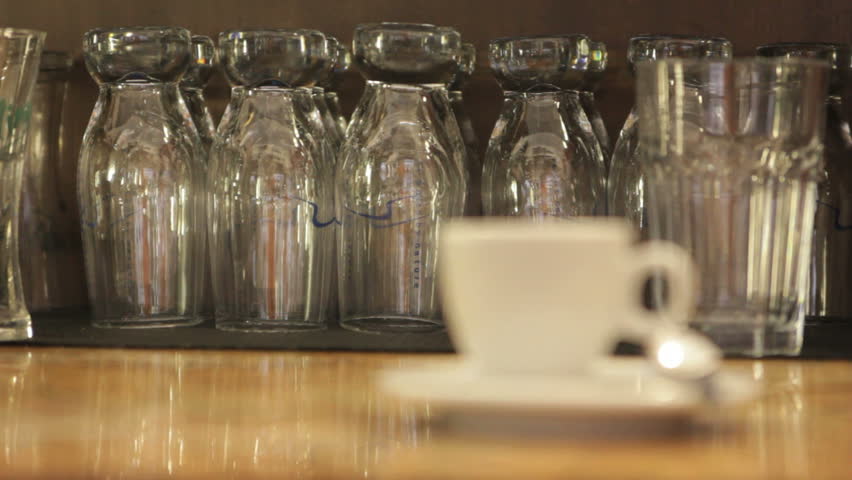 Cup with coffee on a table with a row of glasses as a background / Cup with coffee on a table and glasses