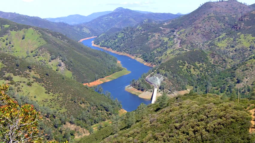 A high and wide shot of the Merced River flowing through the Sierra Nevada foothills and into Lake McClure a reservoir that provides drinking water to the central California region. 