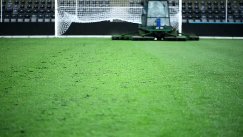 Cutting grass in a football stadium with mowing equipment