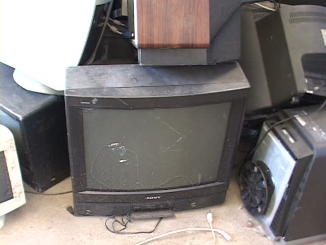 Stacks of discarded computer screens and monitors fill a storage area.