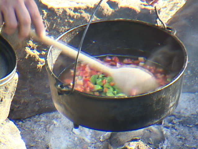 Red and green peppers simmering in a cast iron pot
