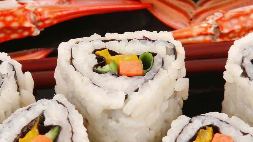 Roll with Cucumber , Cream Cheese with raw Tuna and Salmon inside. on black dish with boiled crab . Japanese traditional Cuisine