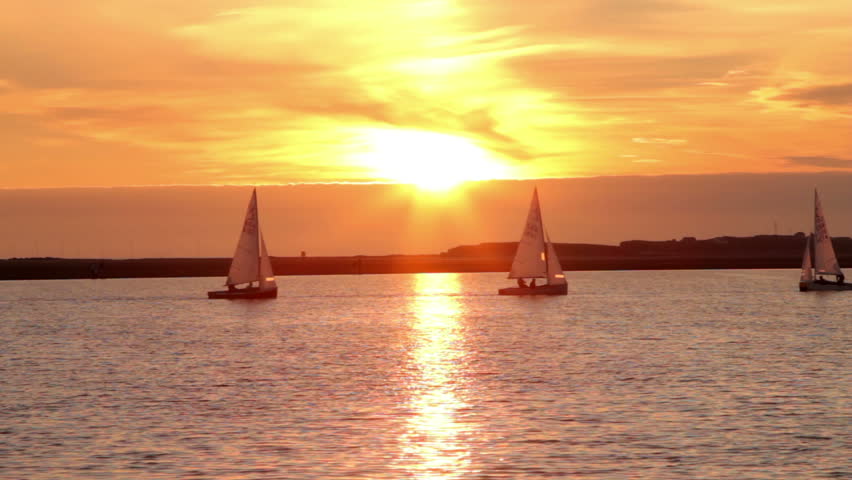 WEST KIRBY, WIRRAL/ENGLAND - AUGUST 9: Sailing boats gently sail on lake at sunset on August 9, 2012 in West Kirby. The Marine Lake is a man made coastal lake fed by the sea at high tide.  