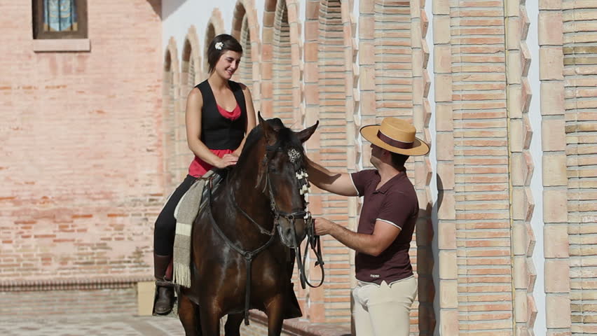 Man chatting to a woman on horseback in a village in Andalusia, Spain