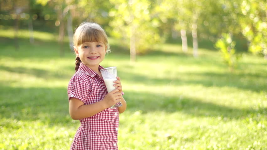 Girl drinking milk outdoors. Thumbs up. Ok.
