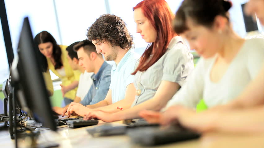 Female young teacher instruct multi ethnic college classmates researching knowledge in technology IT room