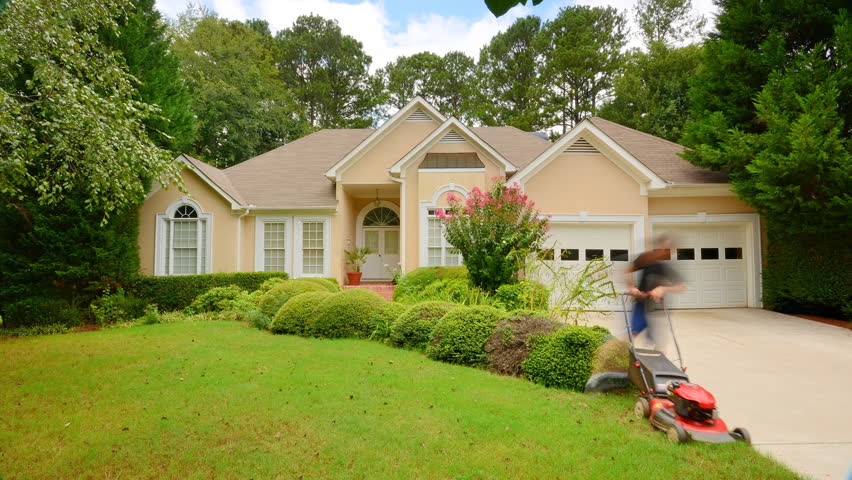 man mowing the grass in front of a house