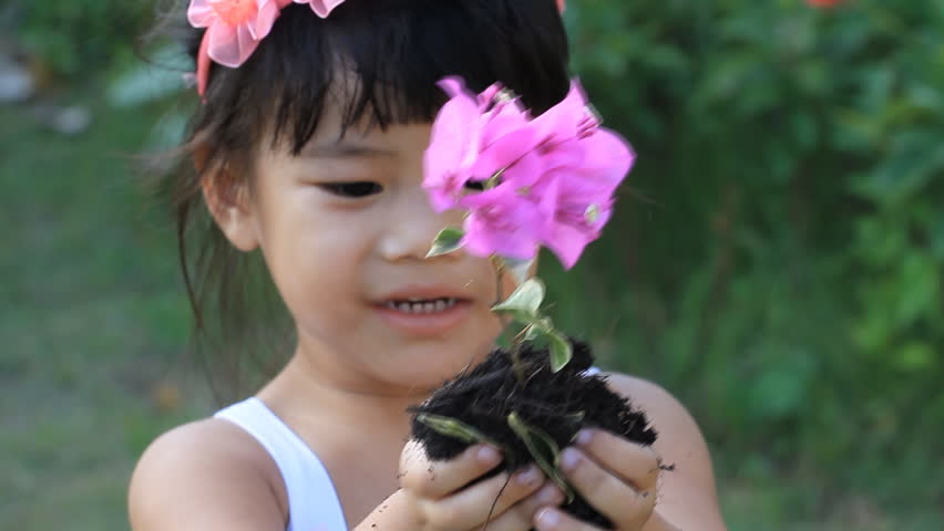 Little Asian girl holding plant 