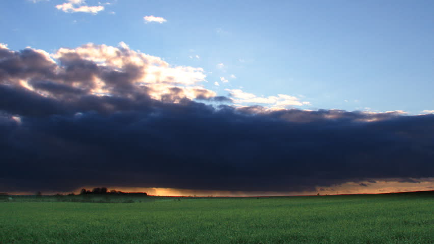 Time lapse sequence of sunset storm clouds passing over fields