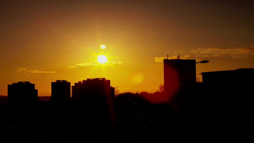Time lapse clip of a sunset against a city scape.