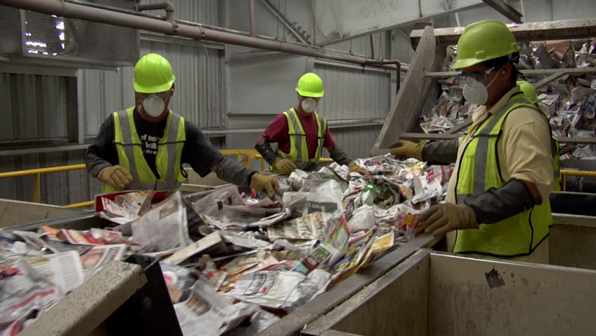 ORLANDO, FLORIDA - CIRCA   2009: Three workers sorting material to be processed in a recycling plant