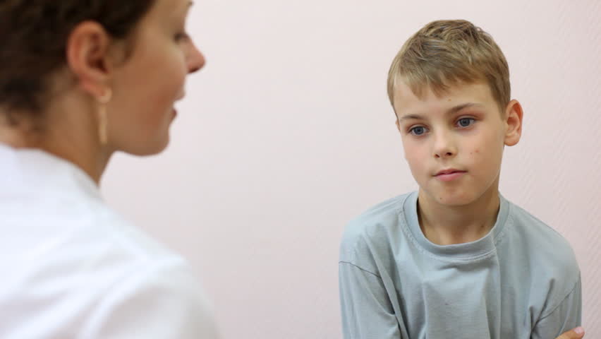 woman doctor takes from boy thermometer from armpit and looks temperature
