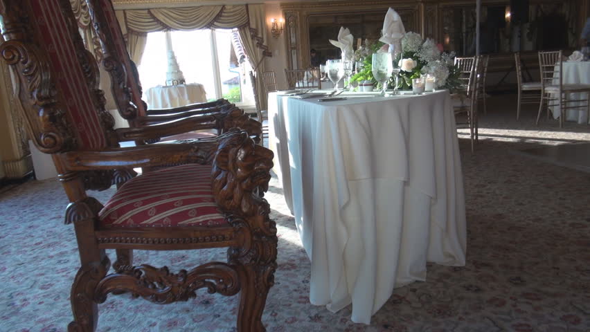 Ornamental chairs close to table with flowers, candles, glasses 