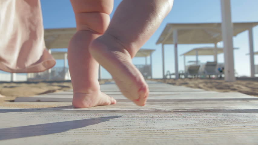 Happy family on the beach. Baby first steps.