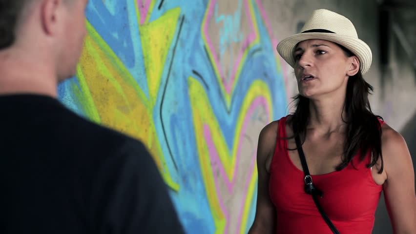 Arguing couple standing in front of graffiti, steadycam shot
