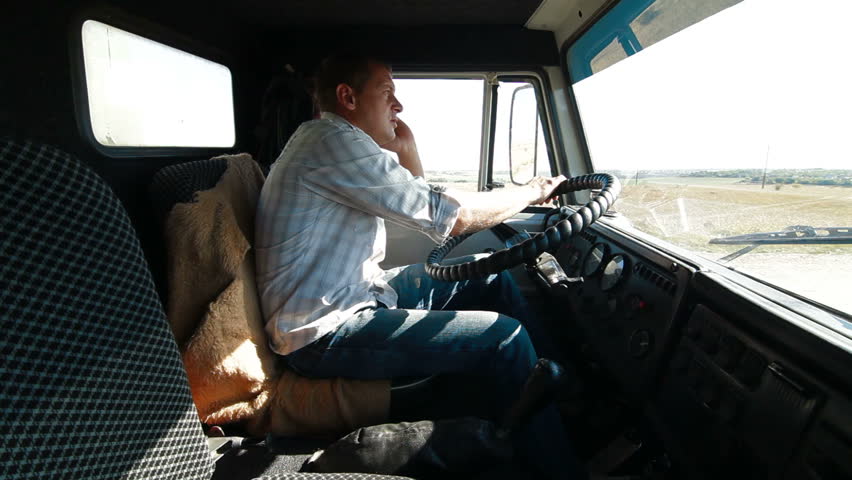 Lorry driver talking on the cell phone at the wheel of truck