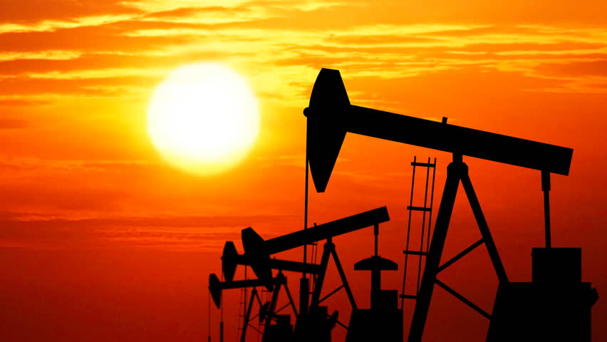 Silhouettes of oil pumps working. Seamless loop. Sun rays in the background.