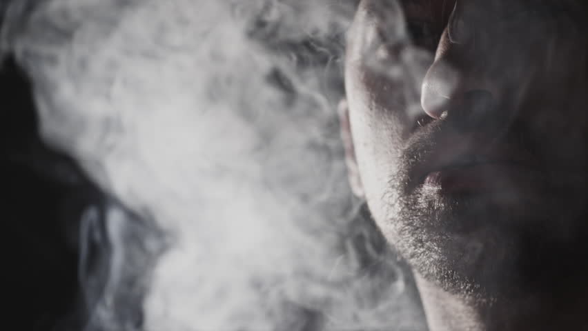 A Man Smokes a Cigar. Takes a big drag and puffs smoke.