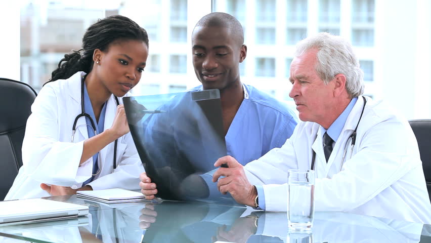 Serious doctors and an intern looking at an x-ray in a bright room