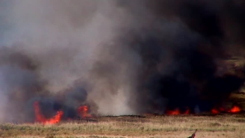 dark smoke billows from a grass fire