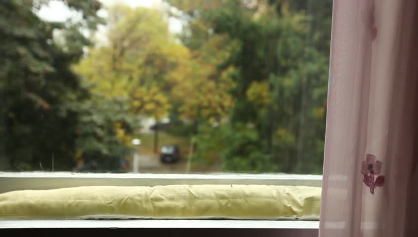 Young adult woman comes to window and speaks to an off camera character.
