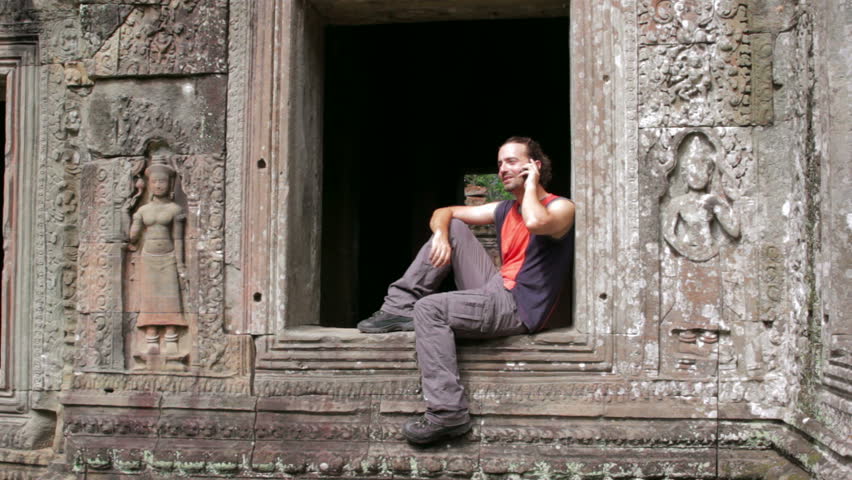 Caucasian tourist talking with mobile phone in Angkor