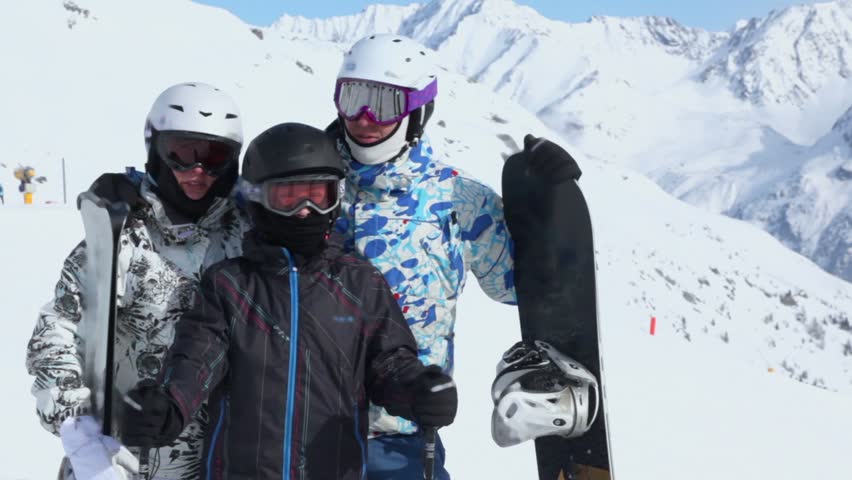 Family stand with snowboards and full ammunition on winter day at mountains