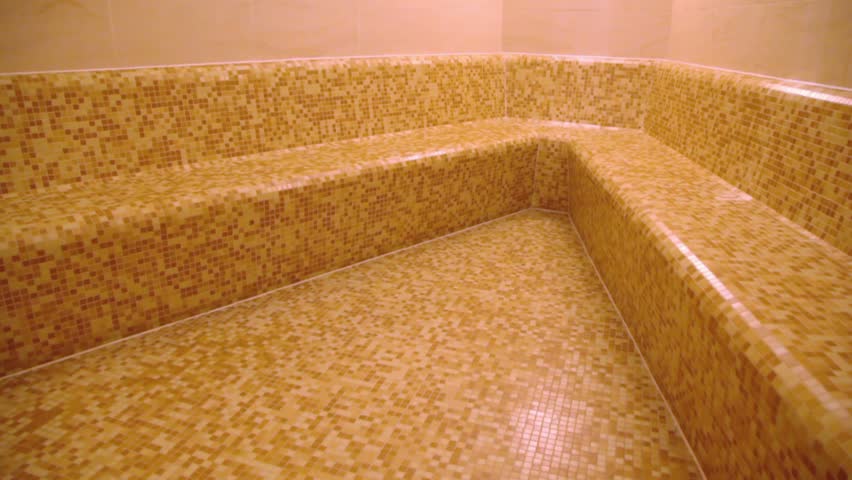 Empty sauna room with tiled wall and seat, shown in motion