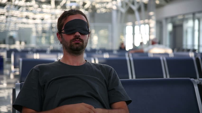 a gentleman sleeping in airport with an eye cover
