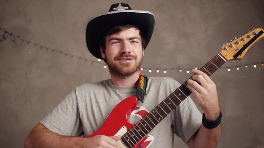 Funny man in cowboy hat playing on guitar while event