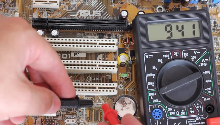 Man measures digital multimeter motherboard and processor.