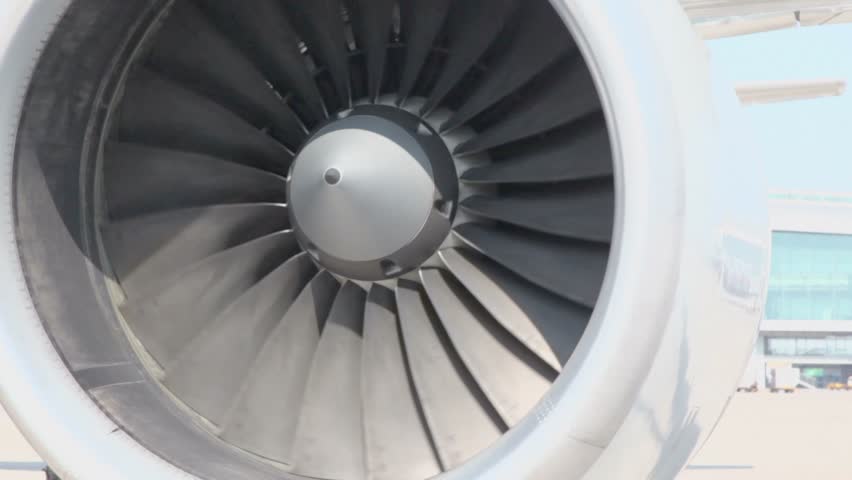 Turbine of airplane spins closeup at sunny day in airport