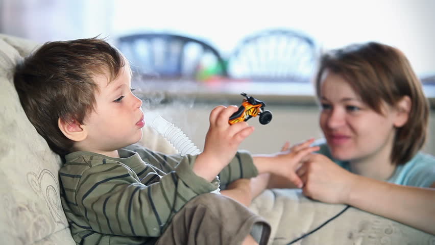 Mother and little boy using nebulizer to inhale medicine, shallow DOF