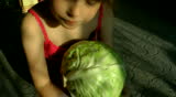 The girl eats, plays about and plays with a head of cabbage