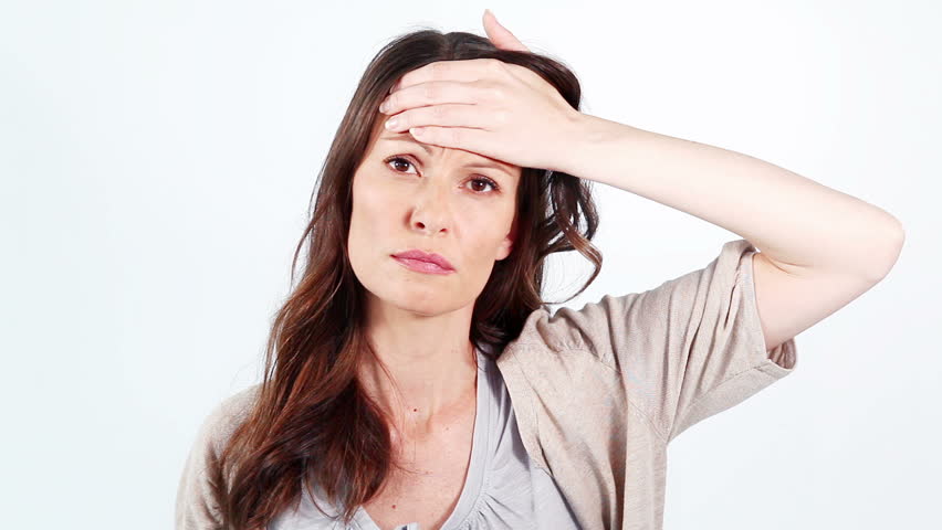 Sick woman measuring her temperature against a white background