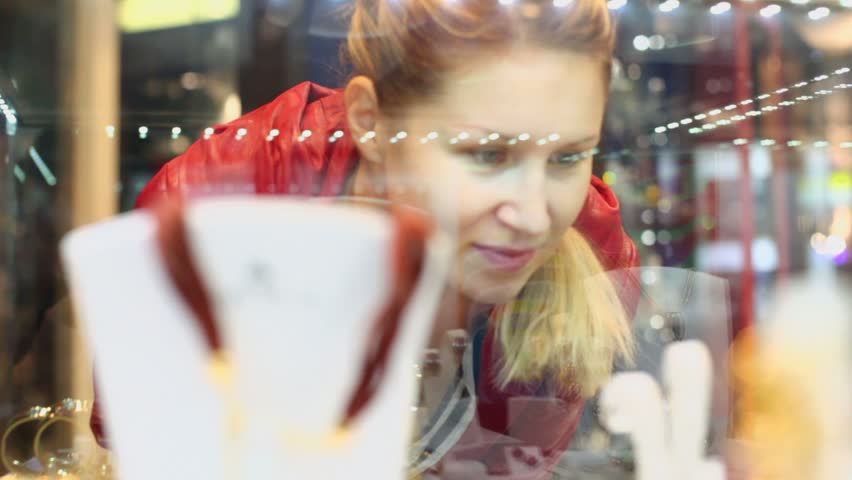 Young woman with braid chooses jewellery in small shop