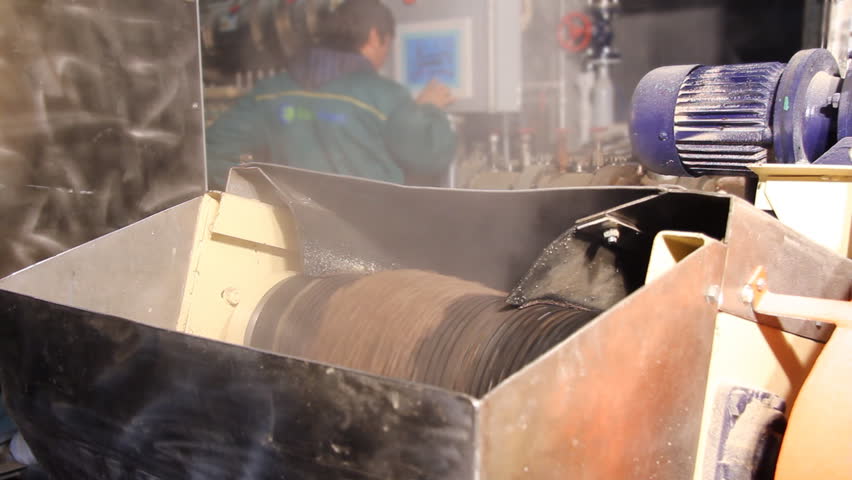 Factory for the production of animal feed. Worker controls grains of processed food