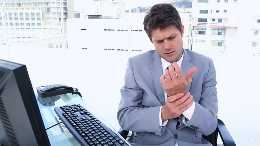 Businessman with sore wrists sitting in his office