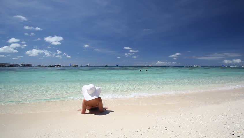 Woman in sun hat relaxing on caribbean beach
