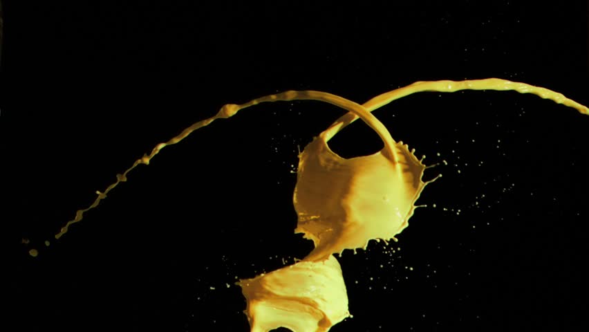 Yellow sprays of paint in super slow motion mixing against a black background
